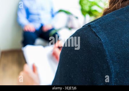 Close Up of Psychologist Hand Taking Notes During Therapy Session with Client Stock Photo