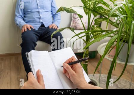 Close Up of Psychologist Hand Taking Notes During Therapy Session with Client Stock Photo