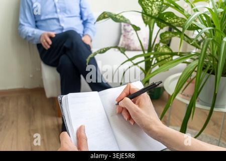Close Up of Psychologist Hand Taking Notes During Therapy Session with Client Stock Photo