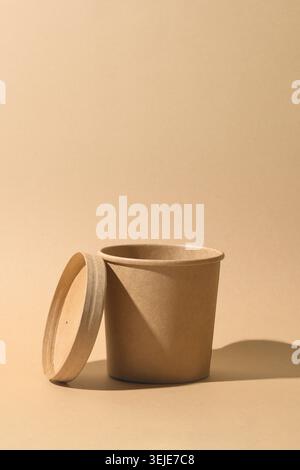 Craft paper soup cup with shadow on brown paper background. Empty container. Ecological individual package. Zero Waste. Stock Photo