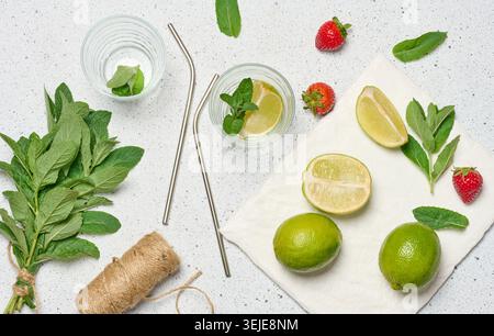 A top down view of ingredients for a refreshing drink, including whole and sliced limes, fresh mint sprigs, two empty glasses, a Stock Photo