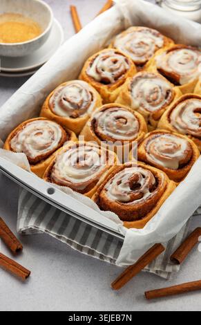 Freshly baked cinnamon rolls drizzled with icing in a baking pan Stock Photo