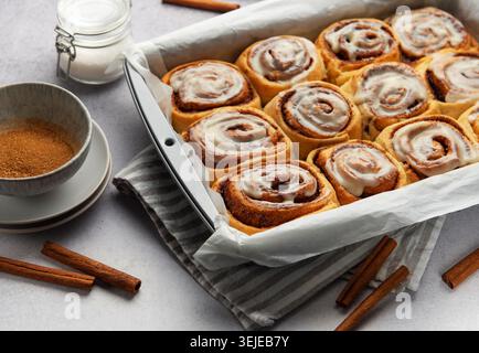 Freshly baked cinnamon rolls drizzled with icing in a baking pan Stock Photo