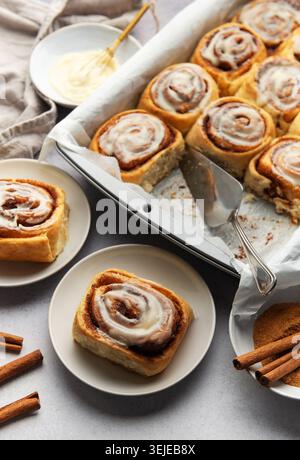 Freshly baked cinnamon rolls with cream cheese frosting and cinnamon sticks Stock Photo