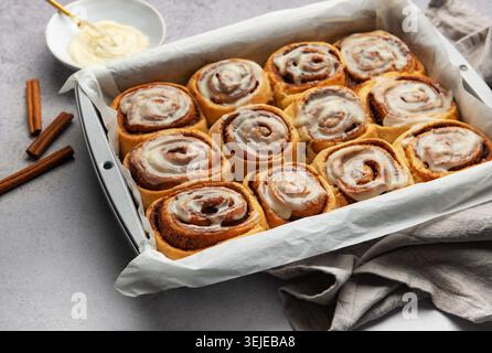 Freshly baked cinnamon rolls drizzled with icing in a baking pan Stock Photo