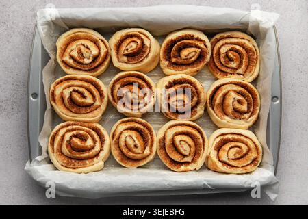 Delicious cinnamon rolls prepared for baking in a rectangular pan Stock Photo