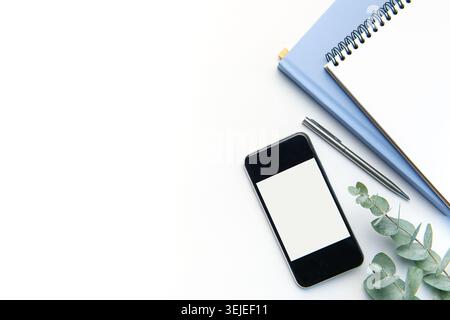 Modern white office desk table with smartphone, notebook and other supplies. Stock Photo