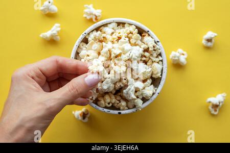 A woman's hand takes popcorn from a cup. Stock Photo