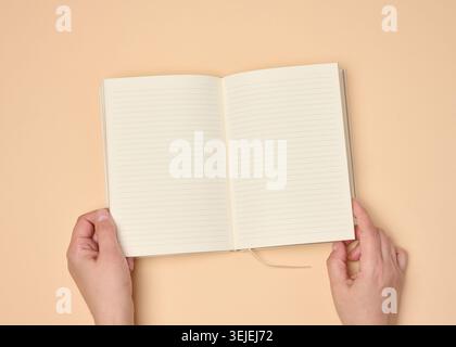 Hands hold a blank open notebook on a neutral background Stock Photo