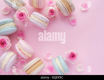 Tasty macaroons with beautiful roses on a pink background Stock Photo