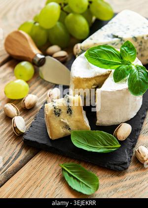 Various types of cheese, grapes and nuts on a old wooden table Stock Photo
