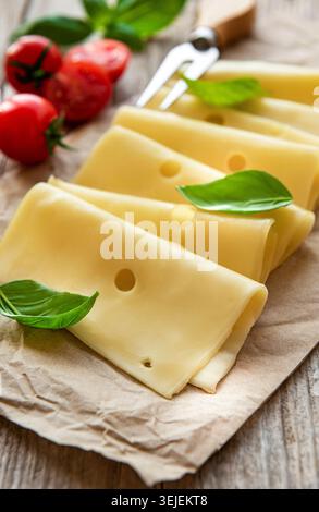 Sliced cheese, basil and tomatoes on a old wooden table Stock Photo