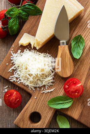 Grated parmesan with basil and tomatoes on a cutting board Stock Photo