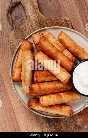 Fried spring rolls with cheese, on a wooden background, with cream sauce, no people, Stock Photo