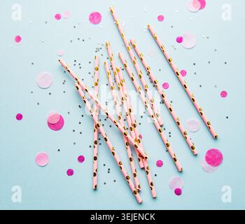 Drinking straws for party and confetti on blue background with copy space. Top view of colorful paper disposable eco-friendly st Stock Photo