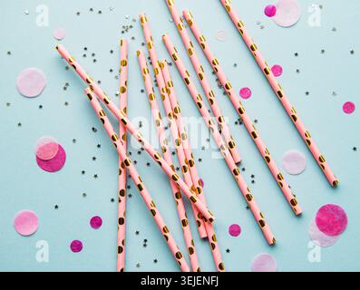 Drinking straws for party and confetti on blue background with copy space. Top view of colorful paper disposable eco-friendly st Stock Photo