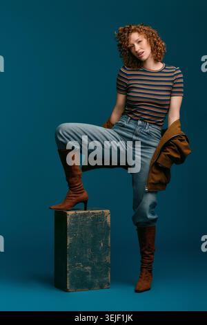 A young woman with curly hair showcases her fashionable style while striking a confident pose. Stock Photo