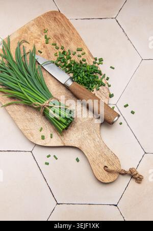 Fresh chopped chives on wooden cutting board Stock Photo