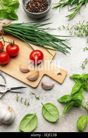 Fresh herbs, spices, tomatoes and garlic creating a frame on kitchen table Stock Photo