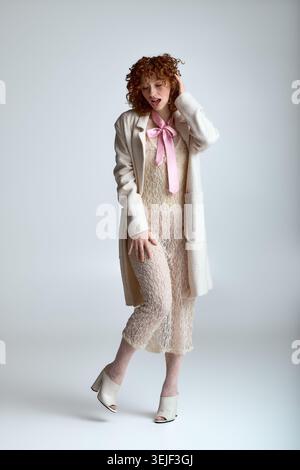 A young, stylish woman stands confidently in a fashionable outfit that showcases her beauty. Stock Photo