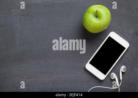 Smartphone and apple on blackboard background Stock Photo
