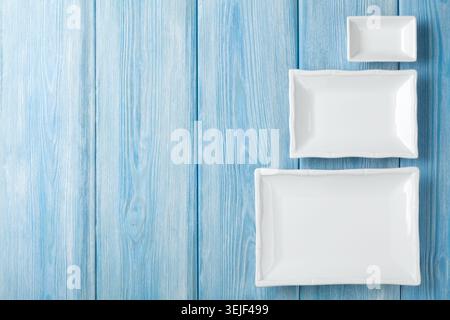 Empty plates and bowls on blue wooden background Stock Photo