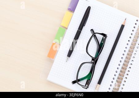 Office table with glasses over notepad, pen and pencil Stock Photo