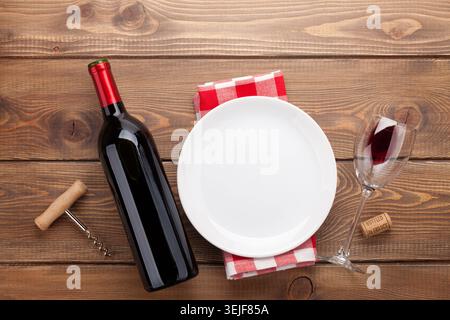 Table setting with empty plate, wine glass and red wine bottle Stock Photo