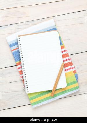 Notepad over kitchen towel on wooden table Stock Photo