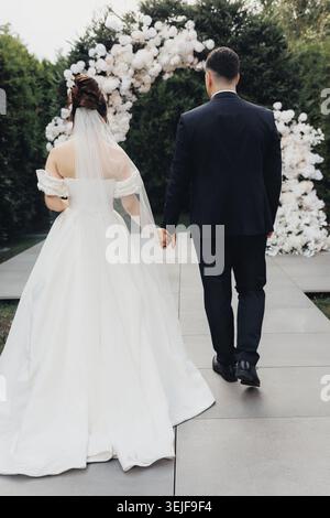 Couple walks hand in hand, back to camera Stock Photo