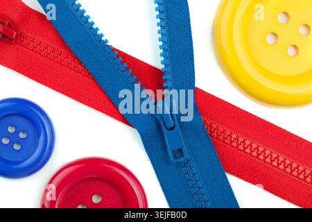 Three colored sewing buttons and two zippers closeup Stock Photo