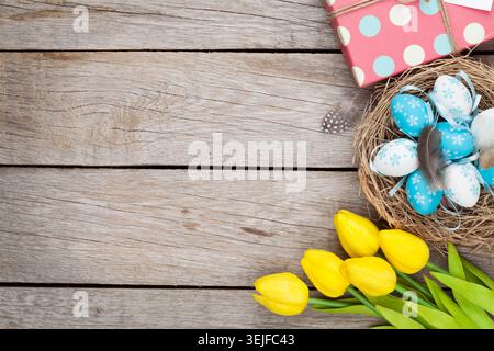 Easter background with blue and white eggs in nest, yellow tulips and gift box Stock Photo