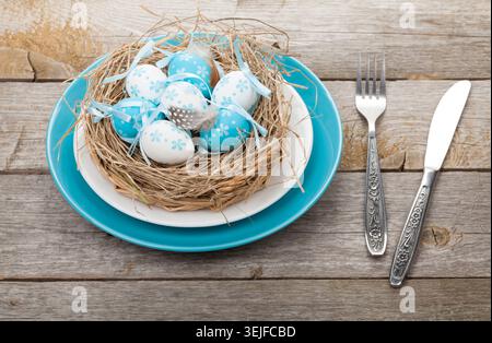 Easter eggs nest on plate over wooden background Stock Photo