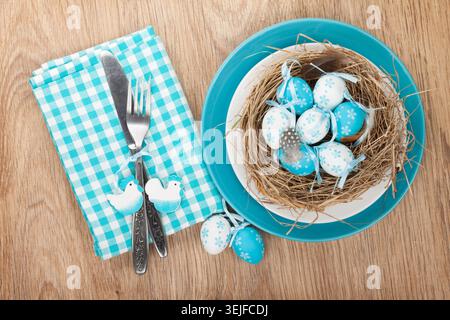 Easter eggs nest on plate over wooden background with silverware Stock Photo