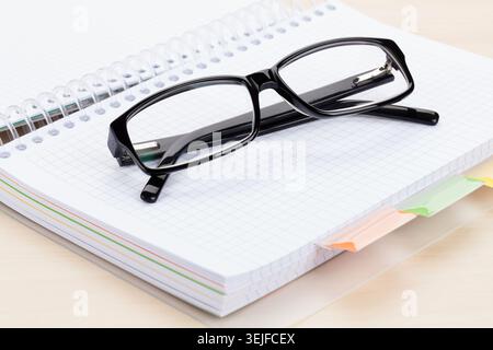 Office table with glasses over notepad Stock Photo