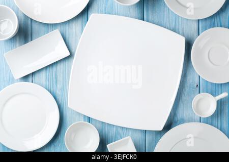 Empty plates and bowls on blue wooden background Stock Photo