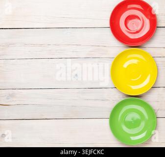 Colorful plates over white wooden table background Stock Photo