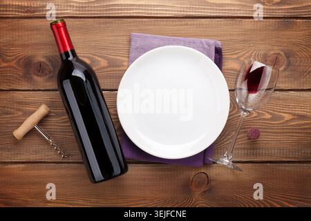 Table setting with empty plate, wine glass and red wine bottle Stock Photo