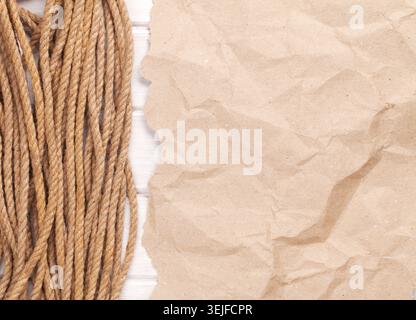 Brown rumpled cardboard paper background with marine rope Stock Photo