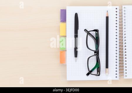 Office table with glasses over notepad, pen and pencil Stock Photo