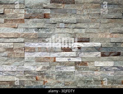 Stone wall paneling made of stacked stripes rock bricks. The colors are white, brown, and gray. Texture. Stock Photo