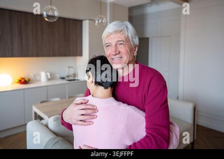 Smiling older man embracing consoling wife tenderly. Old couple relationship support, emotional bond Stock Photo