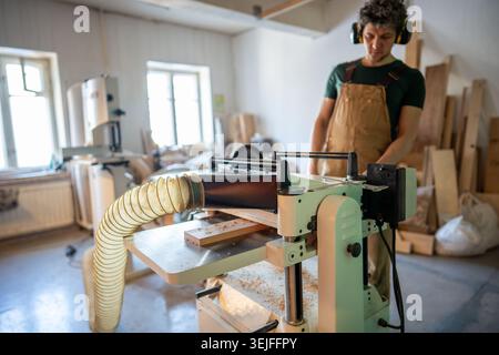 Band saw machine operating. Concentrated craftsman woodworking in studio, finalizing project Stock Photo