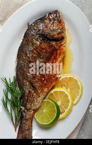 Baked dorado fish, in the oven, fried dorado, with spices and herbs, on a white plate, top view, homemade, no people, Stock Photo
