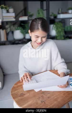 Businesswoman Accountant analyzing investment charts Invoice and pressing calculator buttons over documents. Accounting  at home. Stock Photo