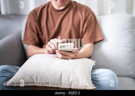 Relaxed young asian man using smart phone  spending time checking news social media. Stock Photo