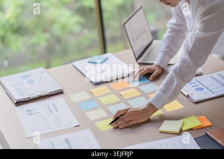 Business People working on sticky notes creative writing down ideas on post it notes professional investor start up project business Stock Photo
