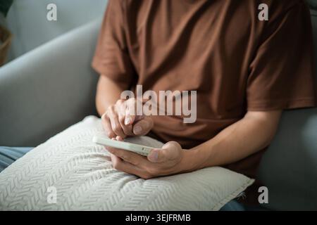 Relaxed young asian man using smart phone  spending time checking news social media. Stock Photo