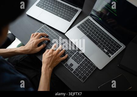 Asian man software engineer Working on Computer at office desk for writing program code IT Software Engineer finding errors tech support devops creati Stock Photo