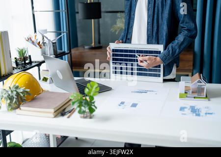 Businessman and Engineers Working on Solar Panels Project for Green Energy Accumulation in Eco-Friendly Office Stock Photo